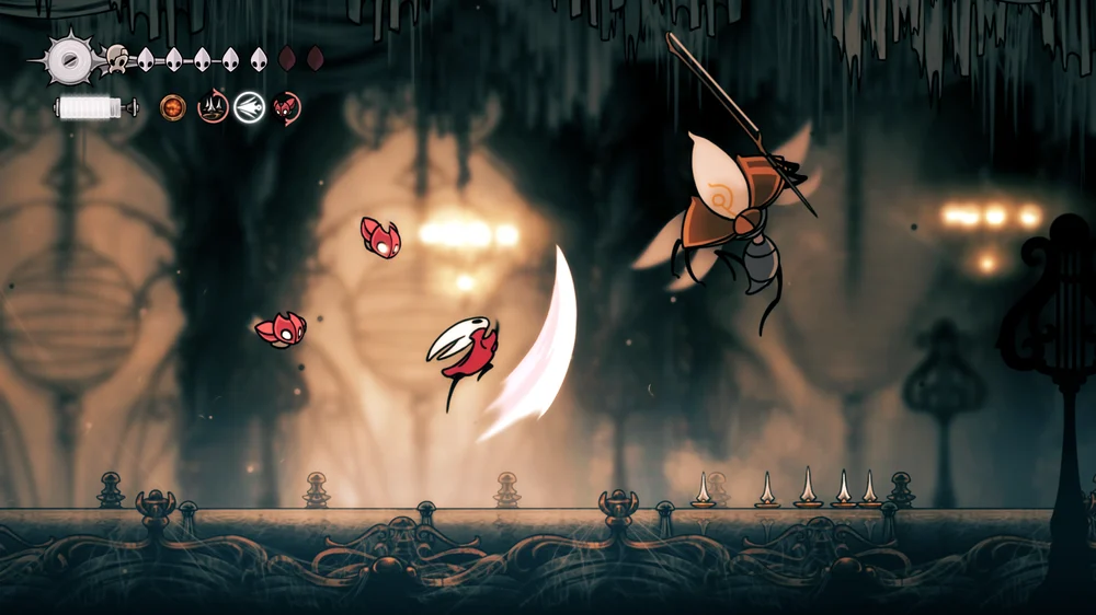 Hornet attacks an airborne enemy above spike-lined platforms.